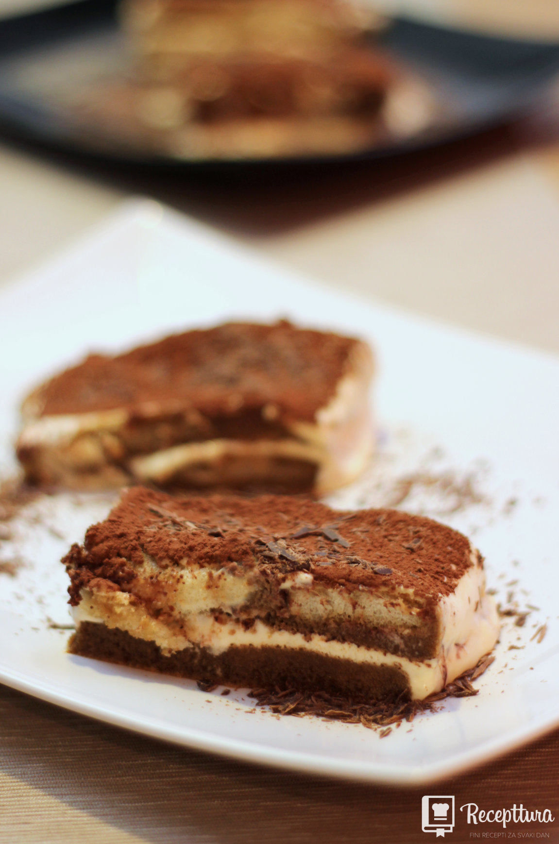 Tiramisu je poslužen na stolu i diskretno ukrašen s malo narezane čokolade.