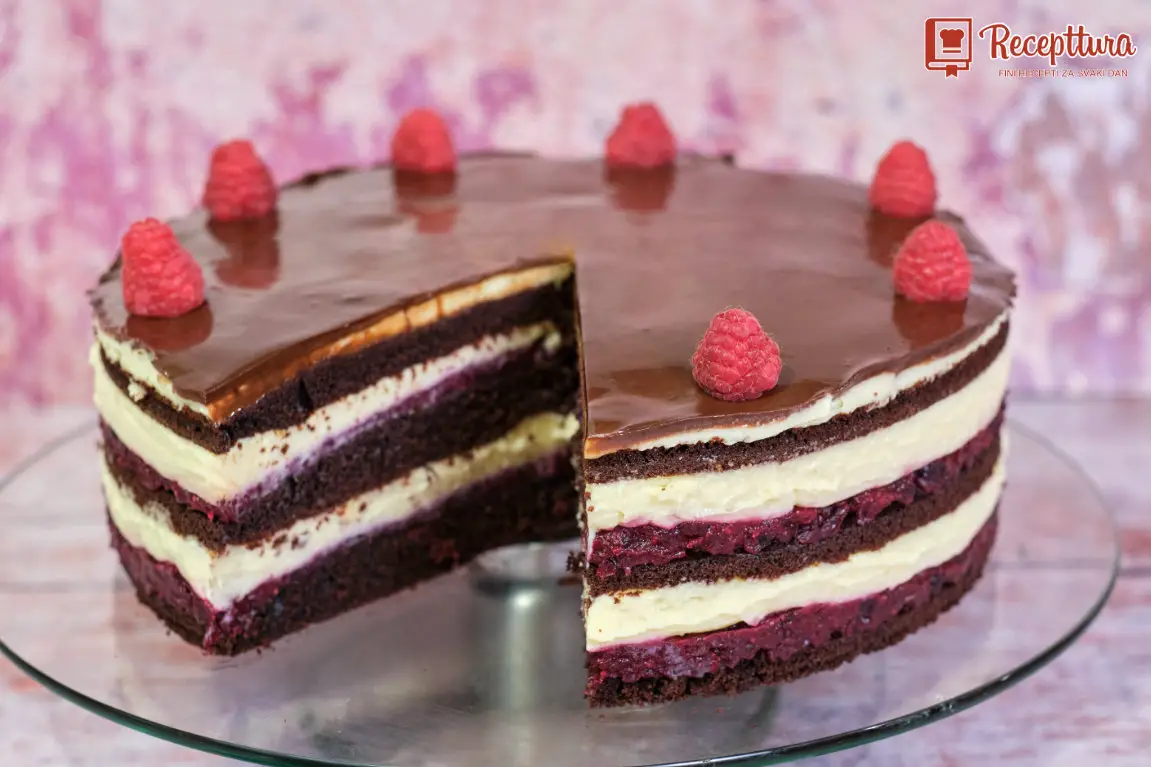 Prerezana Bloody Berry torta koja prikazuje slojeve čokoladnog biskvita, voćne kreme i kreme od vanilije s čokoladnom glazurom