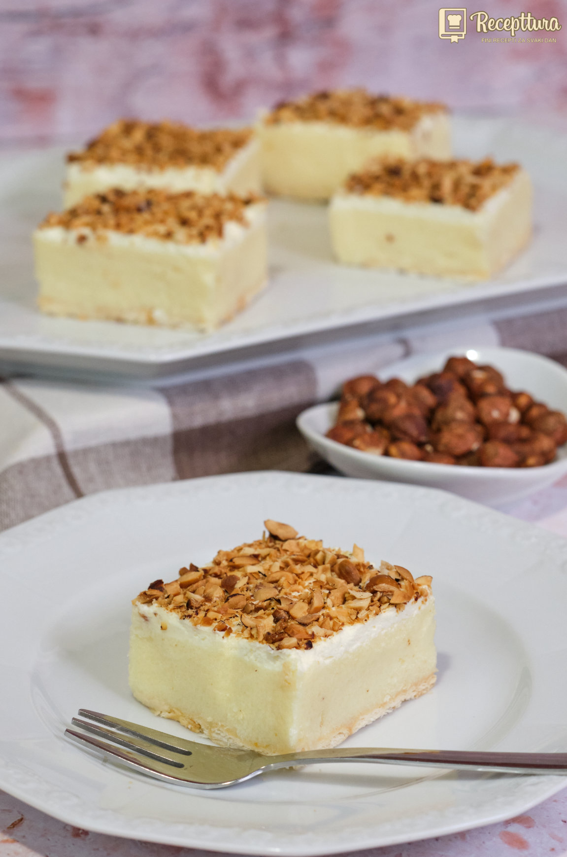Griz kocke bez pečenja – kremasti kolač s keksima, šlagom i preprženim lješnjacima.